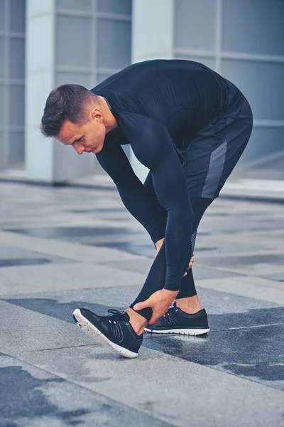 Man stretching outdoors over modern building — Stock Photo, Image