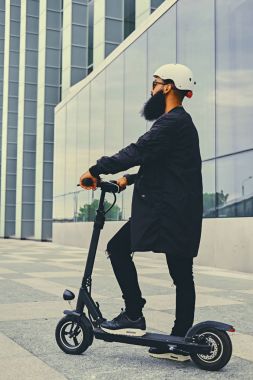 Elektrikli scooter üzerinde poz bir adam.