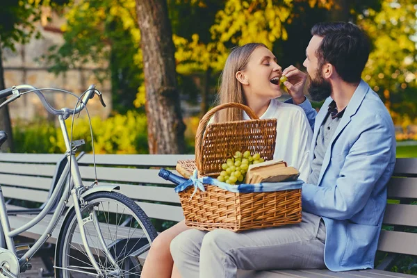 A couple eating grape on a bench — Stock Photo, Image