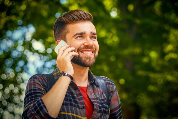 Bearded male talks by a smart phone