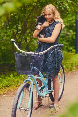 Sarışın kız bir Spitz köpek tutar.