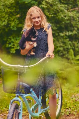 Sarışın kız bir Spitz köpek tutar.