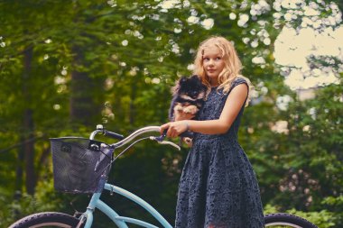 Sarışın kız bir Spitz köpek tutar.