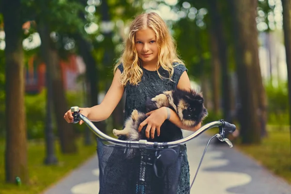 Блондинка на велосипеде и собака-шпиц — стоковое фото