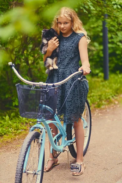 Sarışın kız bir Spitz köpek tutar.