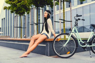 Kadın, yalınayak bir bankta oturur