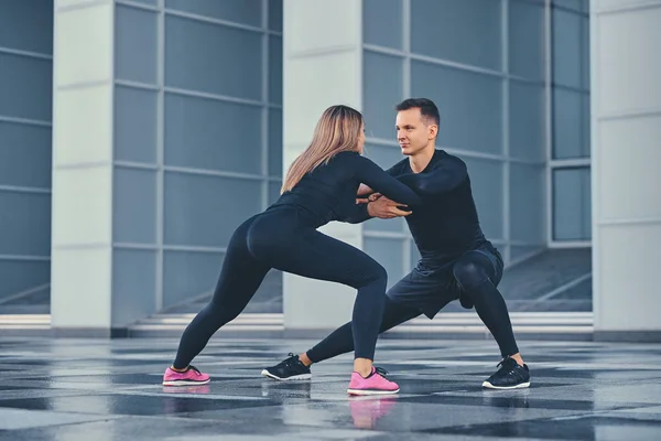 Pareja estirándose sobre edificio moderno — Foto de Stock