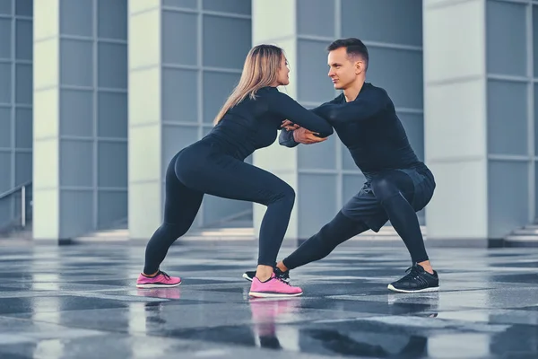 Pareja estirándose sobre edificio moderno — Foto de Stock