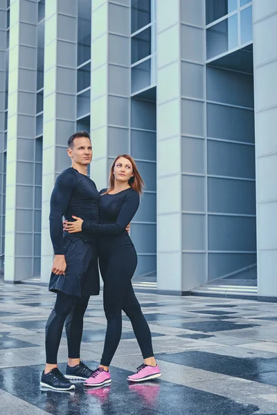 Pareja estirándose sobre edificio moderno — Foto de Stock