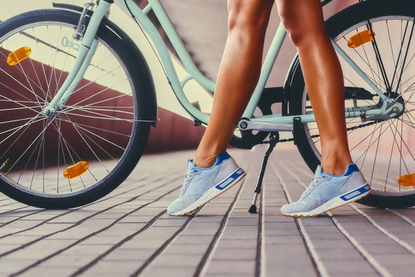 Tan kvinnans ben och en cykel — Stockfoto