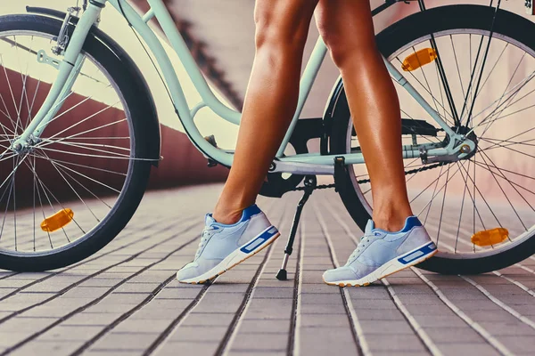 Tan kvinnans ben och en cykel — Stockfoto