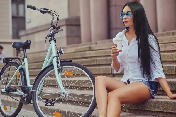 Flickan sitter på ett steg med city cykel — Stockfoto