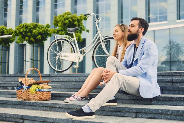 A couple sits on a step with picnic basket. — Stock Photo, Image
