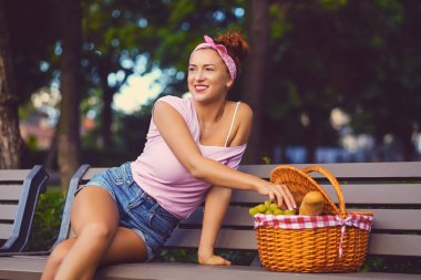 Bir piknik sepeti meyve dolu olan dişi