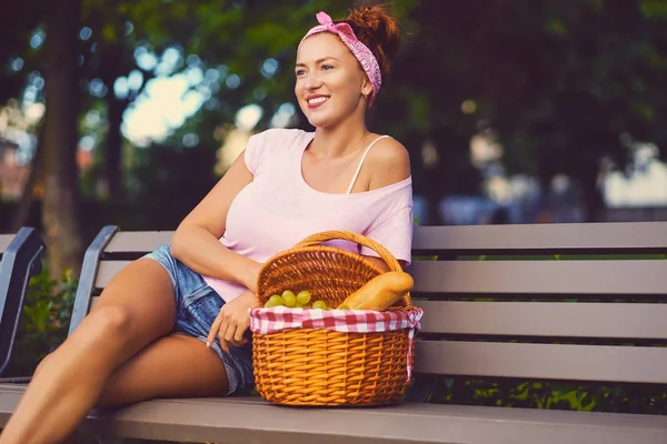 Weibchen mit einem Picknickkorb voller Früchte — Stockfoto