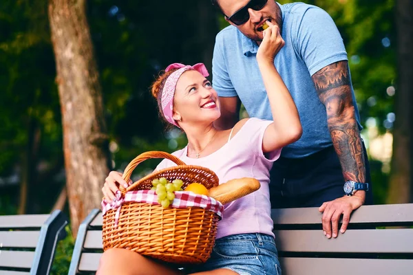 Sakallı erkek ve Kızıl saçlı kadın bir parkta