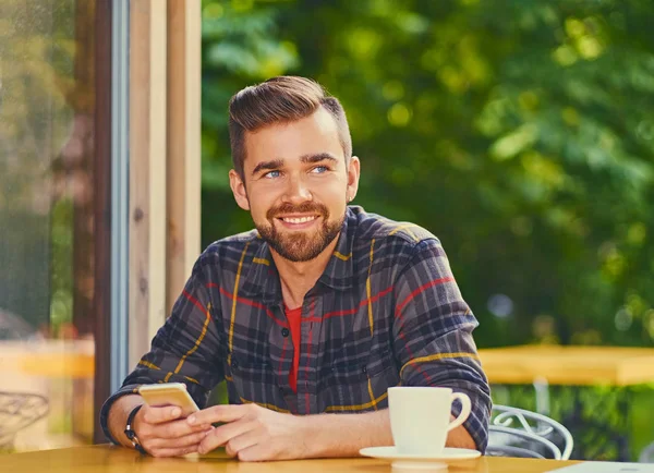 Homme souriant utilisant un smartphone dans un café — Photo