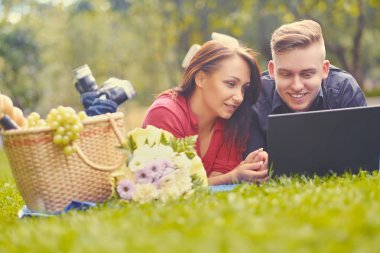 Pikniğe bir dizüstü bilgisayar kullanarak çekici çift