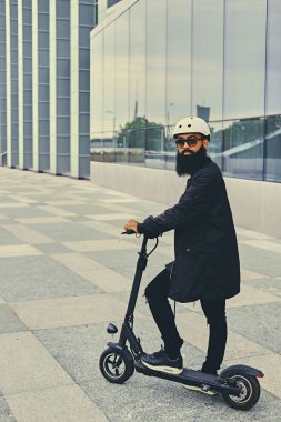 Elektrikli scooter üzerinde poz adam.