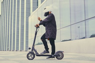 erkek vaping ve tarafından elektrikli scooter sürme