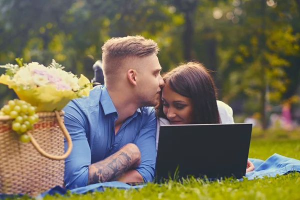 Пара на газоні за допомогою ноутбука — стокове фото