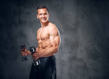 Kaslı erkek dumbbells bir kümesini tutar