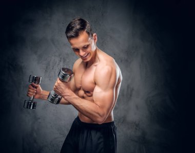 Gömleksiz adam dumbbells bir kümesini tutar.