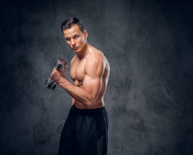 Gömleksiz adam dumbbells bir kümesini tutar.