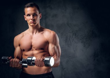 Gömleksiz adam dumbbells bir kümesini tutar.
