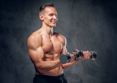 Gömleksiz adam dumbbells bir kümesini tutar.