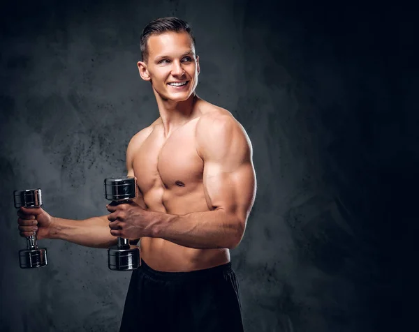 Masculino muscular detém um conjunto de halteres — Fotografia de Stock