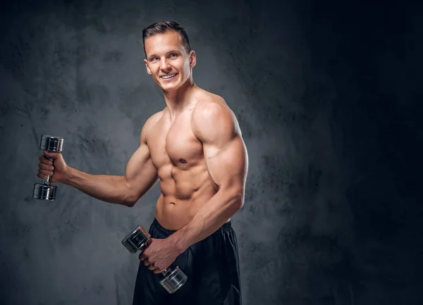 М'язистий чоловік тримає набір гантелів — стокове фото