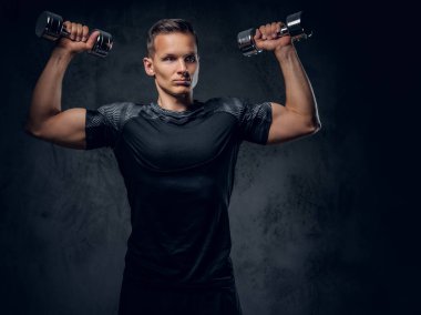 Atletik erkek dumbbells bir kümesini tutar