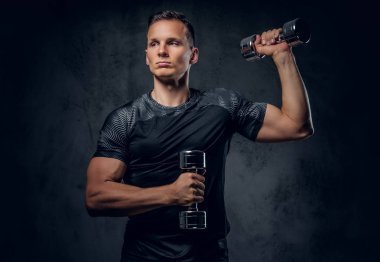 Atletik erkek dumbbells bir kümesini tutar