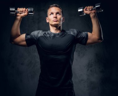 Atletik erkek dumbbells bir kümesini tutar