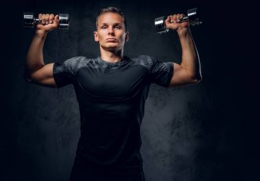 Atletik erkek dumbbells bir kümesini tutar