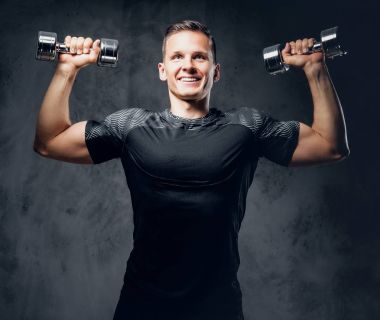 Atletik erkek dumbbells bir kümesini tutar
