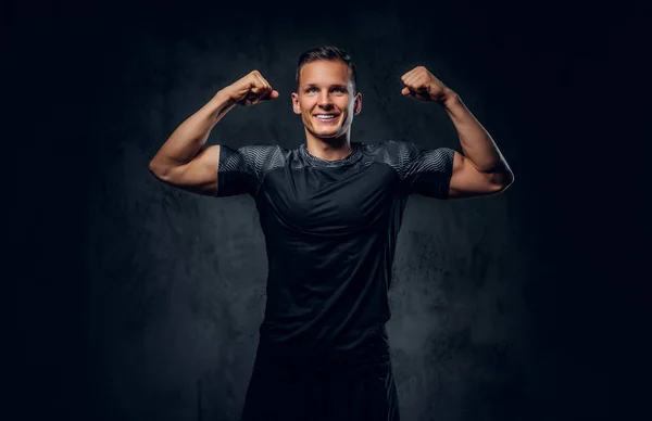 Atletický muž ukazuje jeho biceps. — Stock fotografie