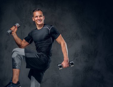 Atletik erkek dumbbells bir kümesini tutar