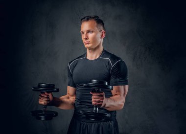 Atletik erkek dumbbells bir kümesini tutar