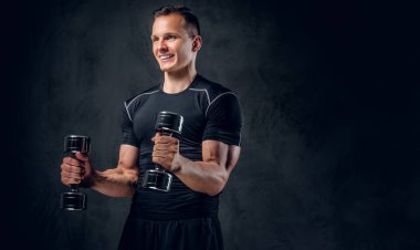 Atletik erkek dumbbells bir kümesini tutar
