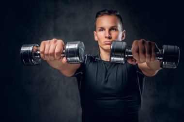 Atletik erkek dumbbells bir kümesini tutar
