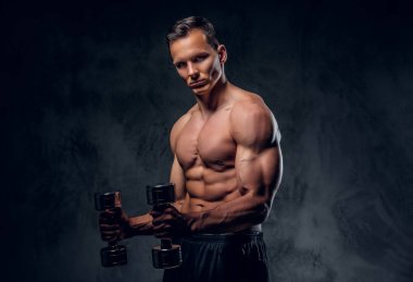 Gömleksiz adam dumbbells bir kümesini tutar.