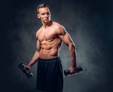 Gömleksiz adam dumbbells bir kümesini tutar.