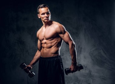 Gömleksiz adam dumbbells bir kümesini tutar.