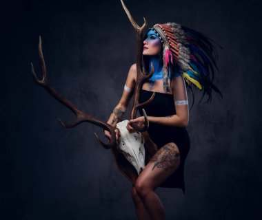 Hintli erkek bir boynuz kafatası tutar.