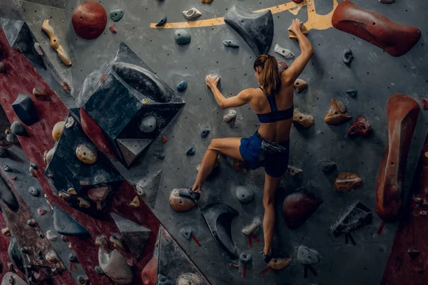 Wspinacz kobiece bouldering w pomieszczeniu. — Zdjęcie stockowe