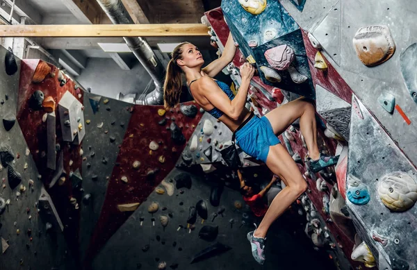 Professional female climber on a bouldering wall. — Stock Photo, Image