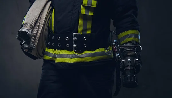 Bombeiro de uniforme mantém mangueira de fogo . — Fotografia de Stock