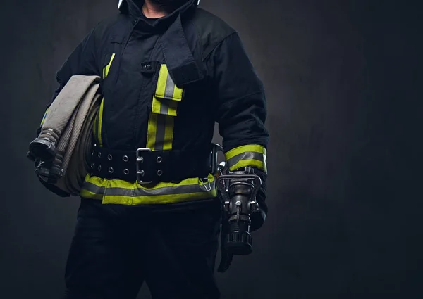 Bombero en uniforme sostiene manguera de fuego . — Foto de Stock